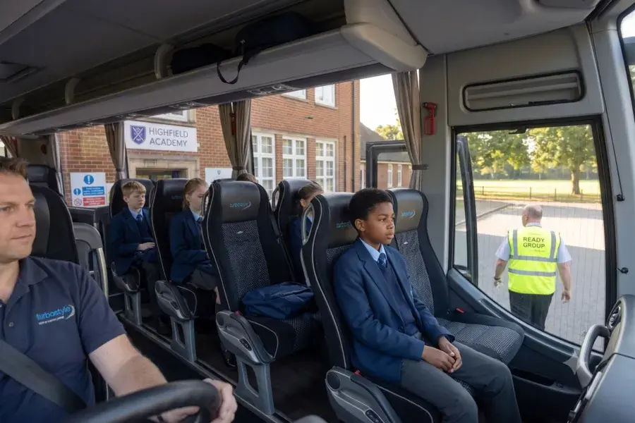 Interior shot looking from the front driver's seat toward students sitting in black upholstered Turbostyle seats inside the coach.